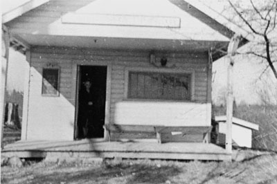 Above is the old logging camp building donated to be used as the library that burned in Nov. 1941. The librarian standing in the door is Mrs. Hildreth Engler who was the librarian at the time. She circulated books from her house until the new library opened in May 1942. Photographer: Bob Downing (One of Mrs. Engler's young patrons). Photograph Courtesy of the Photograph courtesy of the Alderwood Manor Heritage Association, circa 1940.